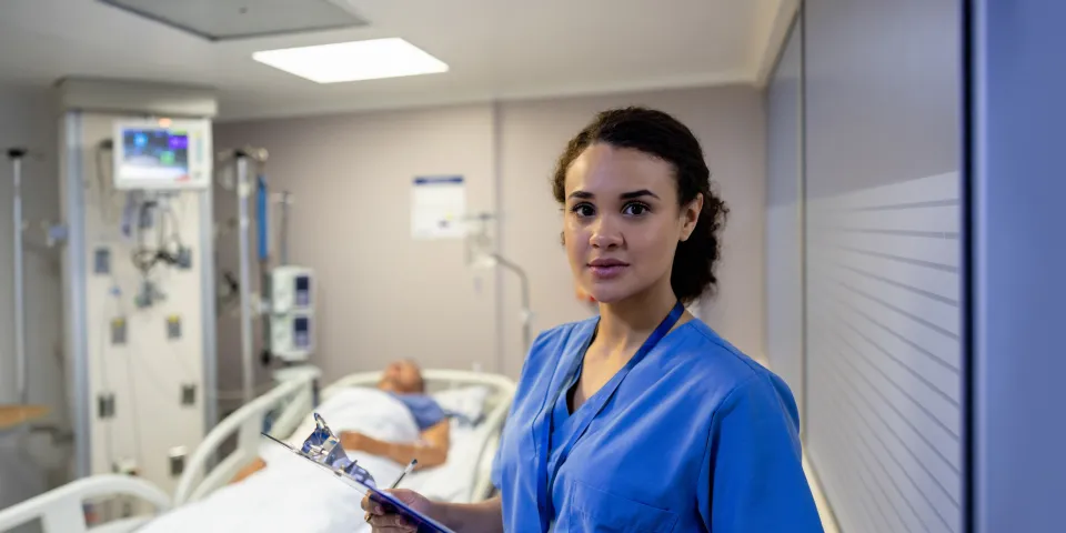 Portrait of a Latin American nurse working at the ICU and checking on a patient - healthcare and medicine concepts