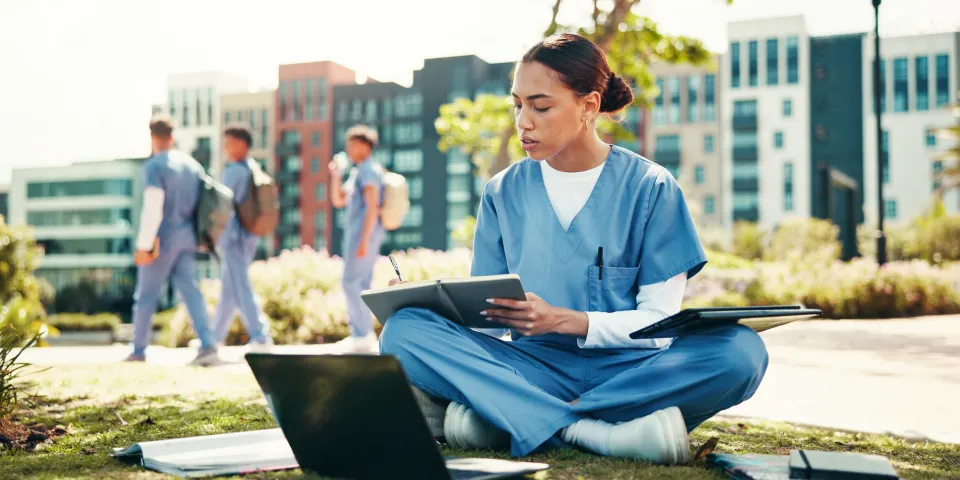 Woman, nurse or student writing with book for internship, studying or research at med school. Female person, healthcare candidate or intern taking notes with laptop for medical exam or test at campus