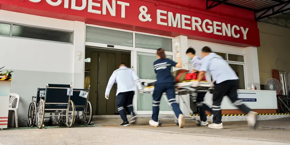 Team of emergency medical service workers wheeling patient on stretcher into the hospital during an emergency situation
