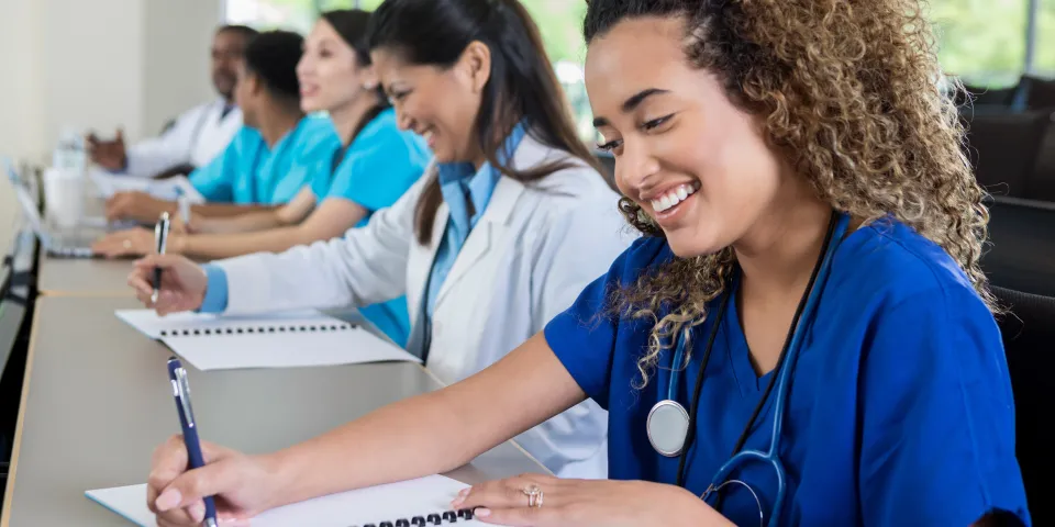 Beautiful female medical or nursing school student smiles as she takes notes during class.