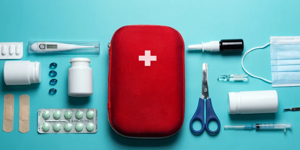 Home first aid kit on a blue background. The elements of the first aid kit