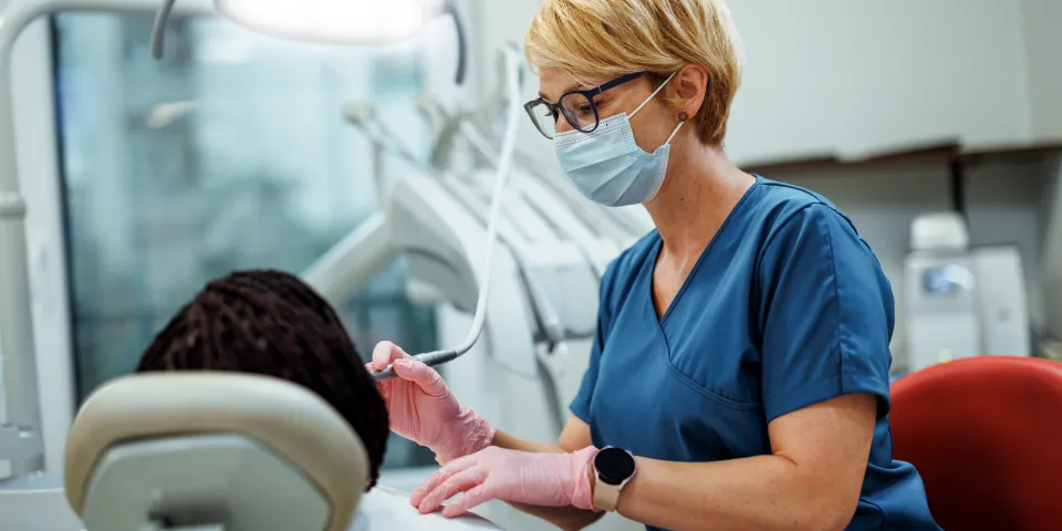 Professional female dentist performing dental treatment on a female patient, demonstrating precision, care, and a supportive healthcare environment.