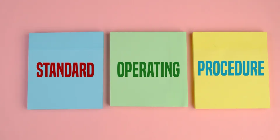 Business Acronym SOP as Standard Operating Procedure. pink background. text on yellow, blue and green paper