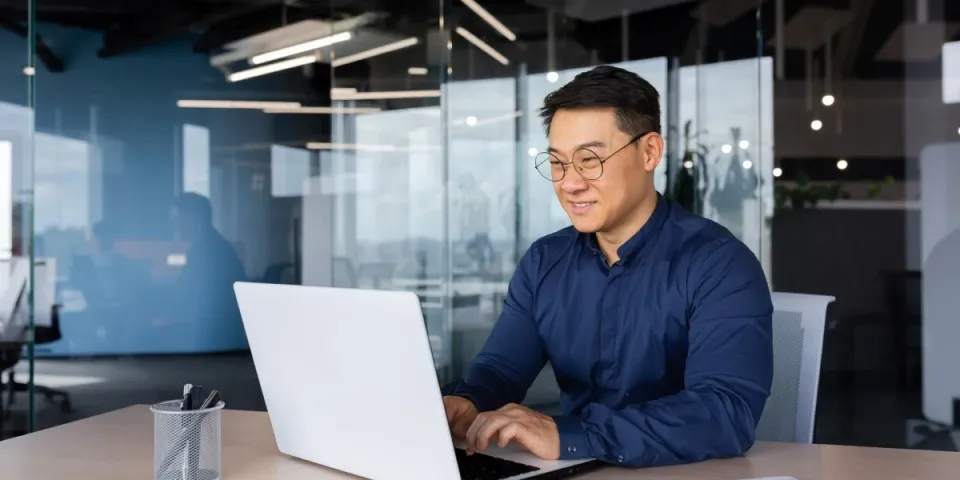 Smiling business professional seated at computer in bright conference room.
