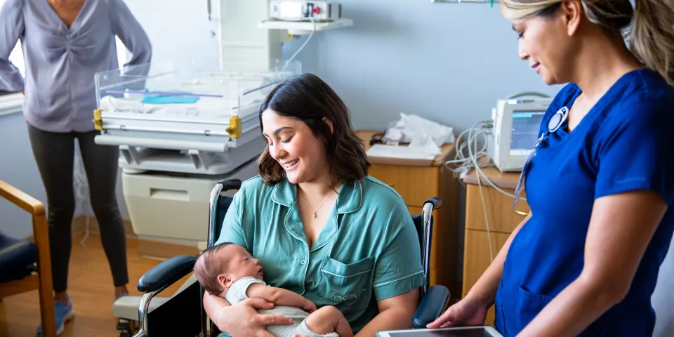 A young family consisting of a hispanic father and mother and their newborn baby boy in the hospital with grandparents, a nurse, and a pediatrician.