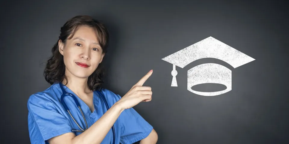 A nurse in blue scrubs points to a graduation cap symbol, representing nursing education, academic achievement, and career advancement.