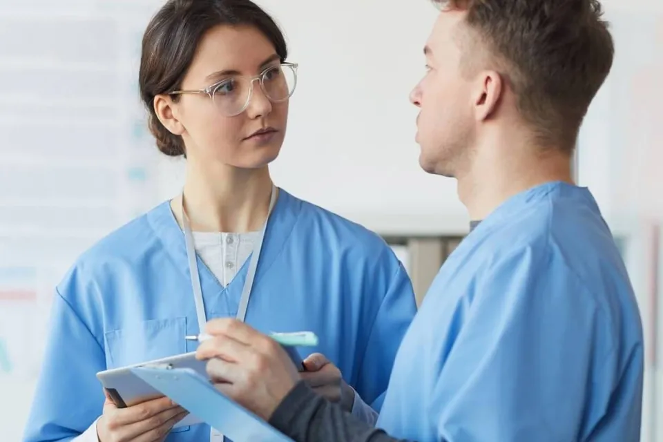 Registered Nurses With Clipboards Discussing Patient Treatment