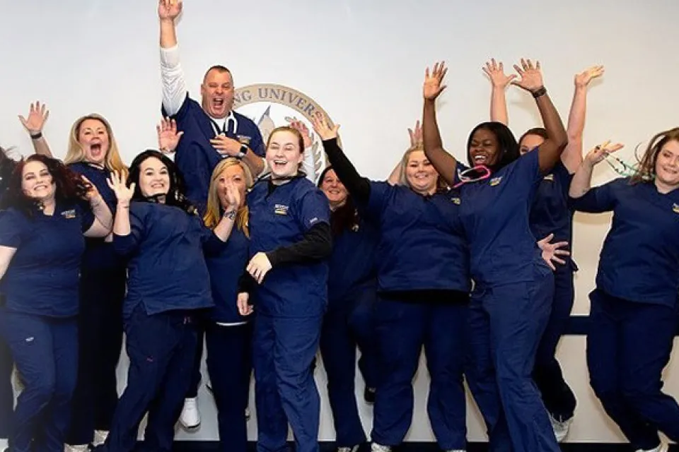 Online BSN nursing school students in scrubs celebrating