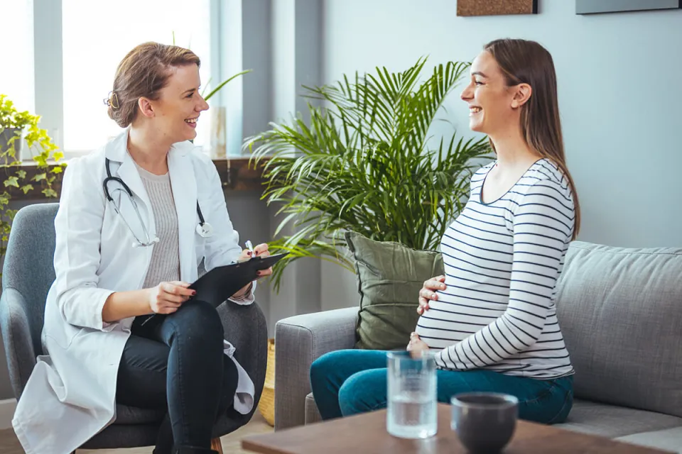 Women's health nurse practitioner smiling with pregnant patient